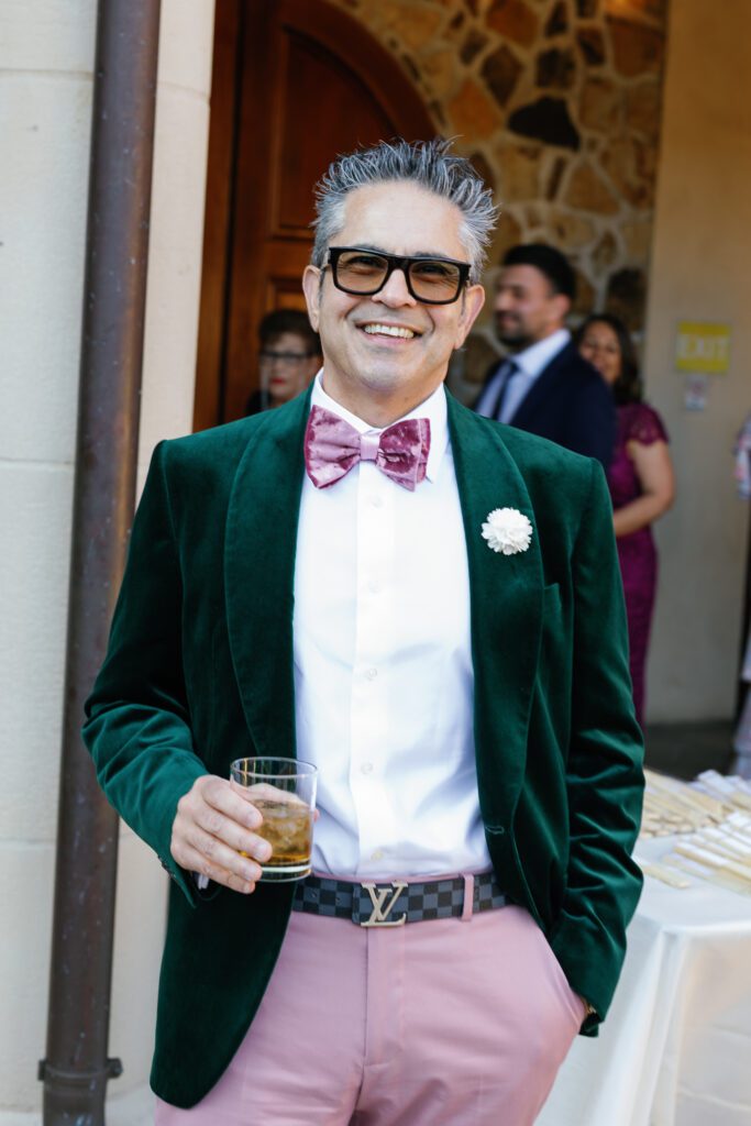 Wedding guest wearing green velvet jacket holding cocktail at Jacuzzi Winery
